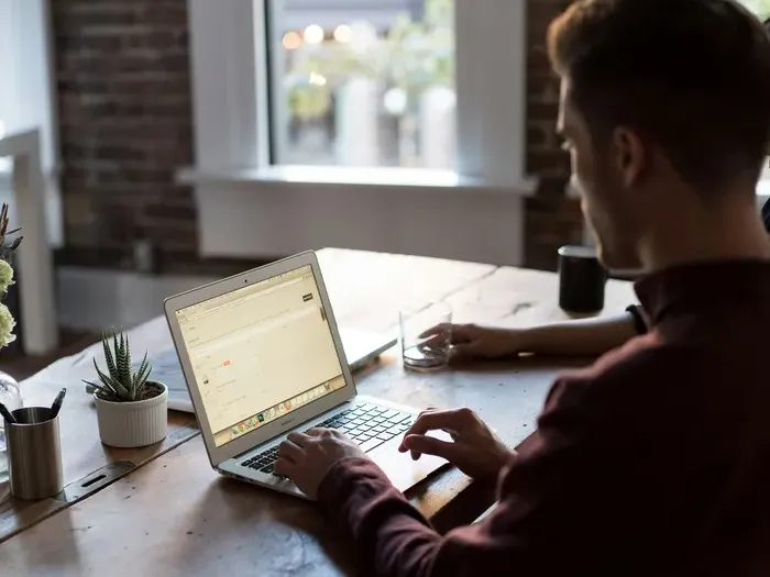 Man at wooden desk working on laptop in bright office, highlighting Local Service Central connecting users with experts